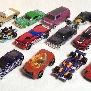 Könnte beinhalten: Eine Sammlung von 18 Miniatur-Spielzeugautos in verschiedenen Farben, darunter Rot, Blau, Grün, Gelb, Schwarz und Weiß. Die Autos sind aus Metall und Kunststoff und haben verschiedene Stile, darunter Sportwagen, Lastwagen und Rennwagen.