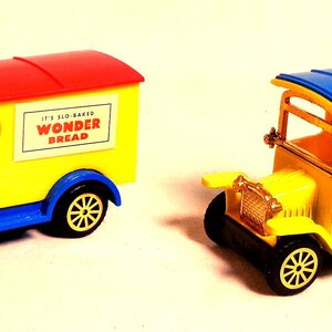 Könnte beinhalten: Zwei Oldtimer-Spielzeug-Lastwagen. Einer ist ein gelb, rot und blaues Wonder Bread Lieferwagen. Der andere ist ein gelb-roter Sunoco-Tankwagen mit blauem Dach. Beide haben schwarze Räder und goldfarbene Akzente.