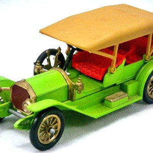 May include: A green toy car with a tan fabric top and red seats. The car has gold-colored wheels and a detailed front grill.