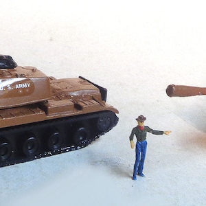 Puede incluir: Dos tanques de juguete marrones con orugas negras y un cañón negro. Los tanques tienen una estrella blanca y las palabras "U.S. ARMY" impresas en el lateral.
