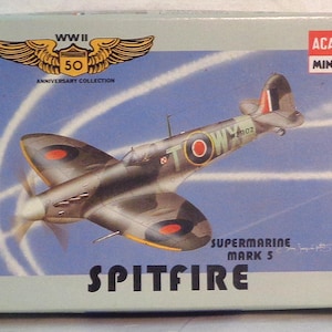 May include: A model kit box featuring a Supermarine Spitfire Mark 5 aircraft. The box has a blue background with white lines and the text "SPITFIRE" in large letters. The box also includes the text "WWII 50 Anniversary Collection".