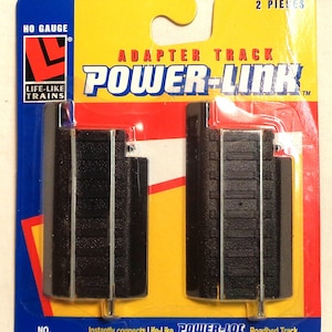 May include: A package of two black and silver HO gauge adapter track pieces for model trains. The package is labeled "Power-Link Adapter Track" and "Life-Like Trains". The package says "Instantly connects Life-Like POWER-LOC. Roadbed Track to Bachmann® E-Z Track™, Atlas® True Track™ and all Standard Track".