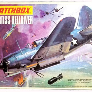 May include: A vintage Matchbox 1/72nd scale model kit of a blue Curtiss Helldiver dive bomber airplane. The box art depicts the plane in flight, with a white star on the tail and the number 37 on the side. The box also includes the text "MATCHBOX" and "CURTISS HELLDIVER".