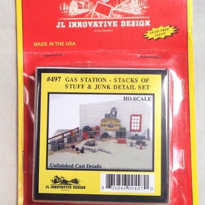 Puede incluir: Kit de modelo para un juego de detalles de gasolinera, con montones de cosas y chatarra. El paquete es rojo y amarillo, con el texto "JL Innovative Design" y "Made in the USA". El kit es a escala HO e incluye detalles sin terminar.