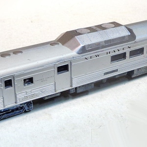 May include: A silver model train carriage with the words "New Haven" printed on the side. The carriage has a United States Mail label and is a passenger carriage.