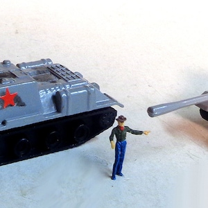 Puede incluir: Dos tanques de juguete grises con estrellas rojas en el lateral. Los tanques tienen orugas negras y están hechos de plástico.