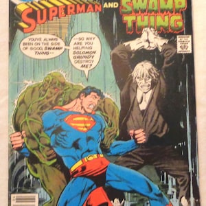 Könnte beinhalten: Ein Comic-Cover mit Superman und Swamp Thing. Superman trägt einen blauen und roten Anzug, während Swamp Thing grün ist und einen großen Kopf hat. Der Text auf dem Cover lautet "DC Comics Presents Superman and Swamp Thing".
