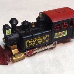May include: Black toy train engine with a red caboose. The engine has gold accents and says "Baltimore and Ohio" on the side. The caboose has a green and yellow number "25" on the side.