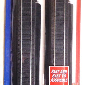 May include: Package of four pieces of HO gauge straight track for model trains. The track is black with silver rails and is labeled "Power-Loc" with the words "Instant Assembly, Automatic Alignment, Perfect Performance".