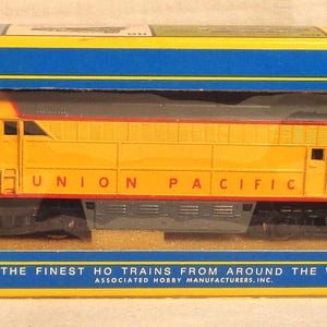 May include: A yellow and red Union Pacific model train in its original box. The train car has the number 1041 on the front. The box is blue and yellow with the text "THE FINEST HO TRAINS FROM AROUND THE WORLD."
