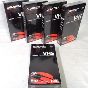 以下が含まれることがあります： オリジナルのパッケージに入った黒いQuantegy Broadcast Video Series VHSビデオカセット5本。各長方形の箱には、白い文字、ColorPlusロゴ、目のアイコンが付いた赤いグラフィック要素があり、T-120およびE-180フォーマットのラベルが貼られています。