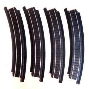 May include: Four black curved train track pieces with silver rails. The track pieces are designed to connect to create a curved section of track.