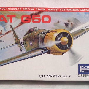 Puede incluir: Una caja de kit de maquetas para un avión Fiat G50 a escala 1/72. La caja presenta una ilustración colorida del avión en vuelo, junto con el texto "FIAT G50" y "1/72 CONSTANT SCALE". La caja también incluye el texto "BONUS! MODULAR DISPLAY STAND. BONUS! CUSTOMIZING DECALS." y un logotipo para "MODEL PRODUCTS BY CRAFT MASTER".