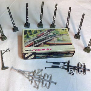 May include: A set of model railway track accessories, including signal poles, points, and a box of track pieces. The box is labelled "Arnold rapido" and "Made in Western Germany".
