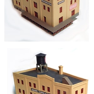 May include: A tan-coloured model building with a water tower on the roof. The building has multiple windows and signs that read "Anchor Cargo & Distributing", "Dependable Auto Parts Distributors", "Distributors", "Cargo", "Distributing", and "Anchor".