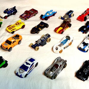 Könnte beinhalten: Eine Sammlung von 25 Spielzeugautos in verschiedenen Farben, darunter Rot, Blau, Grün, Gelb und Schwarz. Die Autos sind alle von verschiedenen Marken und Modellen, und einige haben einzigartige Designs, wie Flammen oder Rennstreifen.