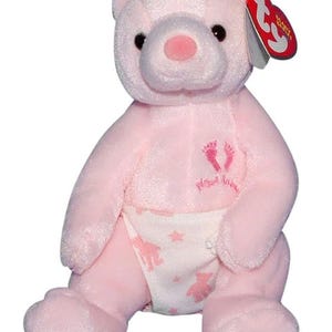 May include: A pink plush bear with a pink nose and black eyes. The bear wears a diaper with a bear and star pattern. The bear has the words "Precious Babies" and footprints embroidered on its chest. A red tag is attached to the bear's ear.