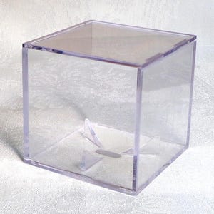 May include: A transparent, square acrylic display case with a lift-off lid. The box is clear, offering complete visibility of the contents. Inside, there are small, clear supports to hold items. Suitable for displaying collectibles or small objects.