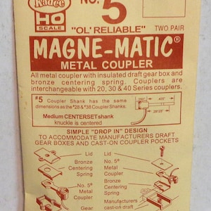 May include: A close-up of a package for Kadee No. 5 "Ol' Reliable" Magne-Matic metal couplers for HO scale model trains. The package features a diagram of the coupler and its components, including the lid, bronze centering spring, metal coupler, and gear box. The text "Simple "Drop In" Design" is also visible on the package.