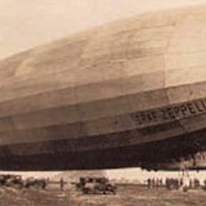 May include: Sepia-toned image of the Graf Zeppelin airship, a large dirigible with the text "GRAF ZEPPELIN" visible on its side. The airship is on the ground with several vehicles and people nearby.