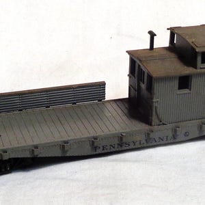 May include: A grey model train car with a wooden caboose. The caboose has a brown roof and the words "PENNSYLVANIA" and "0478" printed on the side.