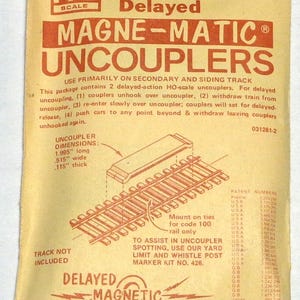 May include: A package for HO scale Magne-Matic uncouplers, featuring the text "321 Two Delayed." The package is orange and white, with diagrams of the uncouplers and track. The uncoupler dimensions are 1.995 inches long, .515 inches wide, and .115 inches thick.