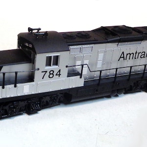 May include: A silver and black Amtrak model train locomotive with the number 784 printed on the side.