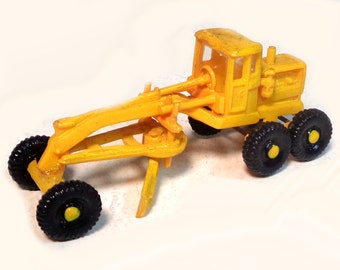 May include: A yellow toy grader with black wheels. The grader has a blade and a cab with a windscreen.