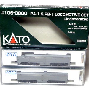 Può includere: Un set di locomotive KATO PA-1 e PB-1 in scatola, non decorate. La scatola è verde e nera con testo bianco, tra cui "#106-0800" e "N Scale". Due modelli di locomotive grigie sono visibili in custodie di plastica trasparente.