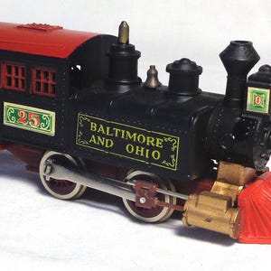 May include: A vintage toy train with a black body and a red roof. The train is labeled "Baltimore and Ohio" and has the number "253" on the side. The front of the train has a red cowcatcher.