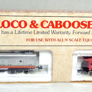 May include: A Bachmann Loco & Caboose Combo set in a cardboard box. The set includes a red and silver locomotive with "SANTA FE" printed on the side, and a red caboose with a yellow roof. The box text reads "LOCO & CABOOSE COMBO".