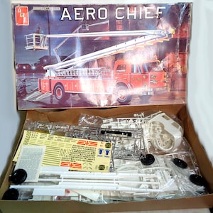 Könnte beinhalten: Ein Modellbausatz eines roten Feuerwehrautos mit einer Leiter, genannt Aero Chief. Die Schachtel zeigt eine detaillierte Illustration des Feuerwehrautos in Aktion. Der Bausatz enthält Plastikteile, Abziehbilder und Anweisungen.