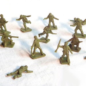Puede incluir: Una colección de pequeños soldados de juguete de plástico verde oliva en varias poses de acción. Algunos soldados están de pie, apuntando con rifles, mientras que otros están arrodillados o tumbados. Las figuras están sobre pequeñas bases rectangulares.
