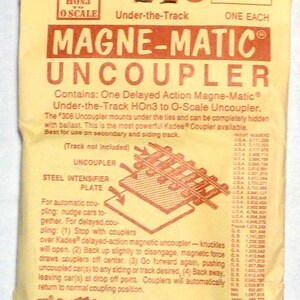 May include: A package for a Magne-Matic Uncoupler, model #308, for HO scale model trains. The package is tan with red text and diagrams, including instructions for use. Made by Kadee Quality Products Co.