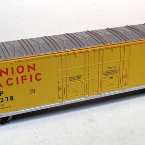 Peut inclure: Un wagon de train modèle de couleur jaune avec un toit gris et "UNION PACIFIC" imprimé sur le côté. Le wagon porte le numéro rouge "UP 451278" sur le côté.