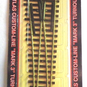 May include: A package containing a HO scale model railroad turnout. The turnout is made of nickel silver and is part of the Atlas Custom-Line "Mark 3" series. The package is labeled with the product number #283 and the description "#6 Left HO Nickel Silver".