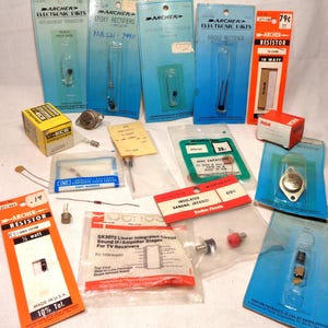May include: A collection of vintage electronic components including Archer transistors, resistors, rectifiers, and capacitors in original retail packaging, alongside loose electronic parts, an RCA box, and a Radio Shack integrated circuit bag.