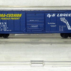 May include: A blue model train car with the text "HYDRA-CUSHION FOR FRAGILE FREIGHT" and "EELX 6151" in yellow. The car also has "D&B LOADER" and other text in white. The model is encased in a clear plastic display case.