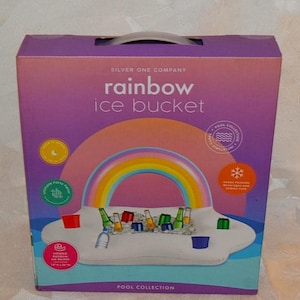 May include: A purple rectangular box for a Silver One Company rainbow ice bucket. The packaging features a graphic of an inflatable white cloud-shaped tray with a rainbow arch, holding various beverage bottles and cups for pool use.