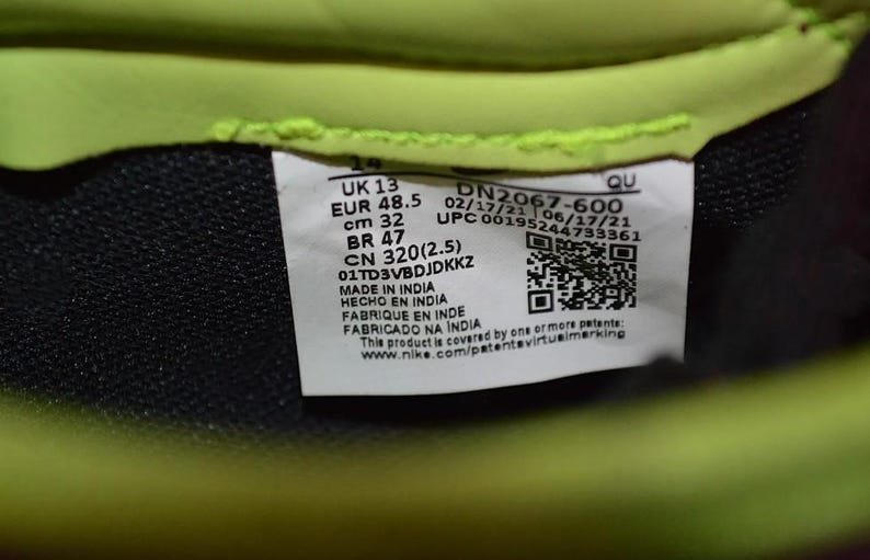 May include: Close-up of a product label with the text "UK 13, EUR 48.5, cm 32, BR 47, CN 320(2.5)". The label also includes a QR code and the text "MADE IN INDIA". The background is black and neon green.