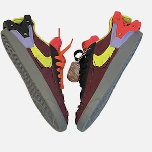 May include: Pair of high-top sneakers in a unique color block design. The shoes feature a burgundy base with yellow, orange, purple, and black accents. The soles are gray, and the laces are orange. A small tag hangs from one shoe.