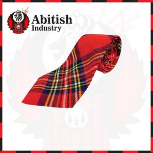 Puede incluir: Una corbata con un vibrante patrón de tartán rojo con líneas que se cruzan en amarillo, blanco, azul y negro. La corbata está enrollada en la parte superior y muestra el texto Abitish Industry con un logotipo que presenta un león y un kilt.