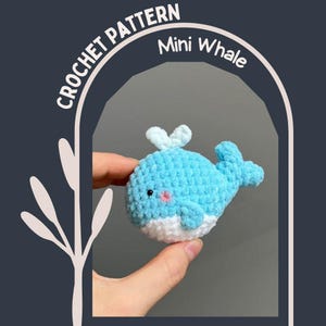 May include: A handmade, mini crochet whale in shades of blue and white. The whale has a small, pink blush and a tiny, light blue spout. The text "CROCHET PATTERN" and "Mini Whale" are displayed in white.