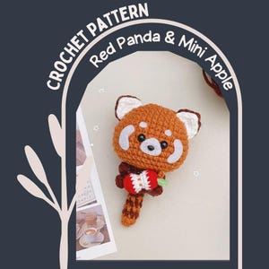 May include: A crocheted red panda toy holding a mini apple. The panda is predominantly brown with white accents. The text "CROCHET PATTERN Red Panda & Mini Apple" is displayed above the panda in a curved format.