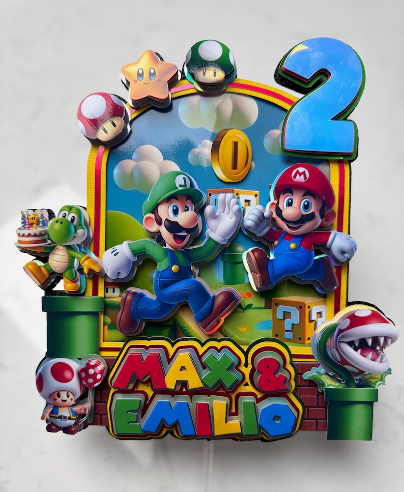 May include: A colorful birthday cake topper featuring Mario and Luigi characters, a large blue number 2, and the names "Max & Emilio". The design includes a coin, a star, mushrooms, and a Piranha Plant.