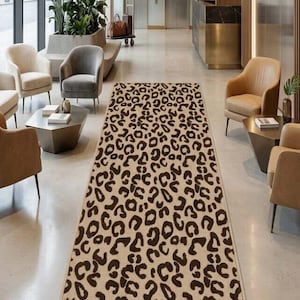 Op de afbeelding: Een rechthoekig beige tapijt met een bruin luipaardprintpatroon. Het tapijt ligt in een gang met neutrale muren, zitplaatsen en een receptie. Het Elara-logo is zichtbaar op de muur.