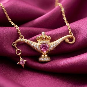 May include: A gold-toned necklace featuring a pendant shaped like an oil lamp with a crown top. The lamp is adorned with small clear stones and a central heart-shaped pink stone. A small star-shaped charm with a pink stone hangs from the side.