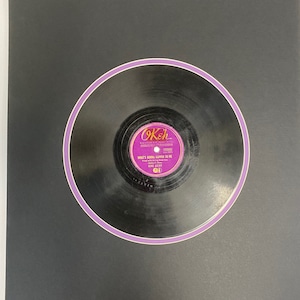 May include: A black vinyl record with a purple border. The record label is pink and says "OKeh" with the text "WHAT'S GONNA HAPPEN TO ME" and "GENE AUTRY" underneath.
