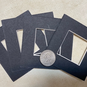 May include: Four black mat boards with white cut-out openings for framing photos or artwork. The boards are approximately 4 inches by 4 inches.