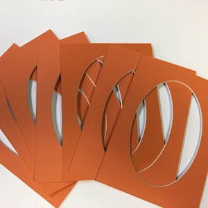 May include: Six orange cardstock mats with oval cutouts. The mats are stacked on top of each other.
